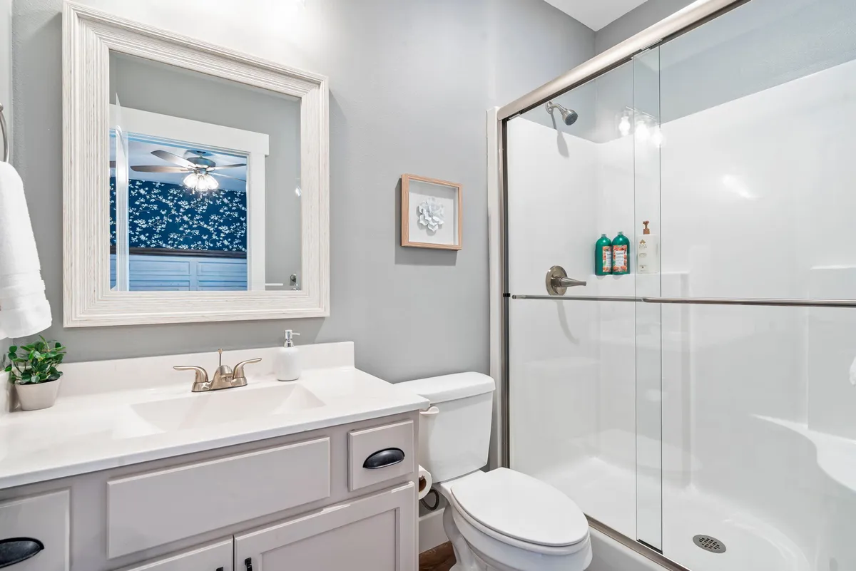 A modern ensuite bathroom with a vanity, framed mirror, and a walk-in shower, all designed in a refreshing, tranquil style. The space is immaculate and bright, showcasing the high standard of cleanliness and comfort provided.