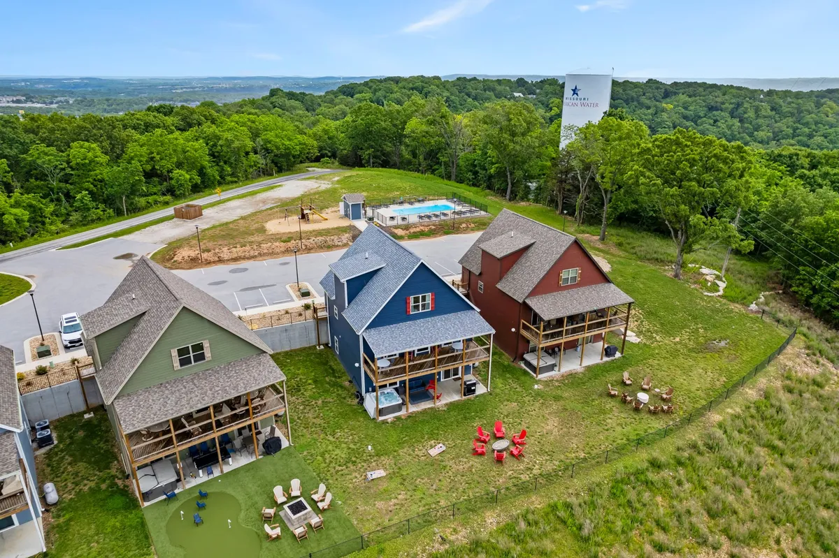 This exterior image captures the colorful Dogwood Place homes arranged around a landscaped yard, with a clear view of the pool area, fire pit, and surrounding green trees. Children can be imagined playing on the lawn while adults relax by the fire or pool, encapsulating the essence of family-friendly outdoor amenities in a boutique setting.
