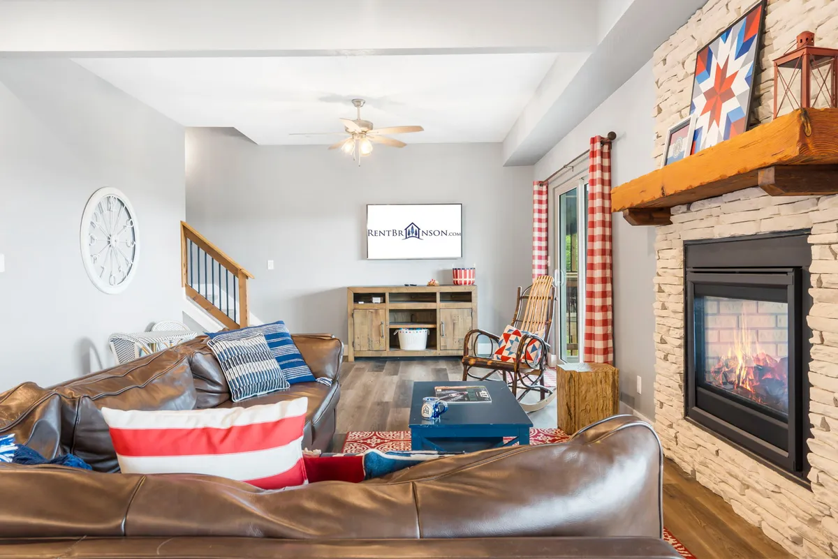 A welcoming living area with a leather sofa, fireplace, coffee table, TV, and rocking chair, creating an inviting space for relaxing and gathering. The setting exudes warmth and comfort, perfect for unwinding together after a day of adventure.