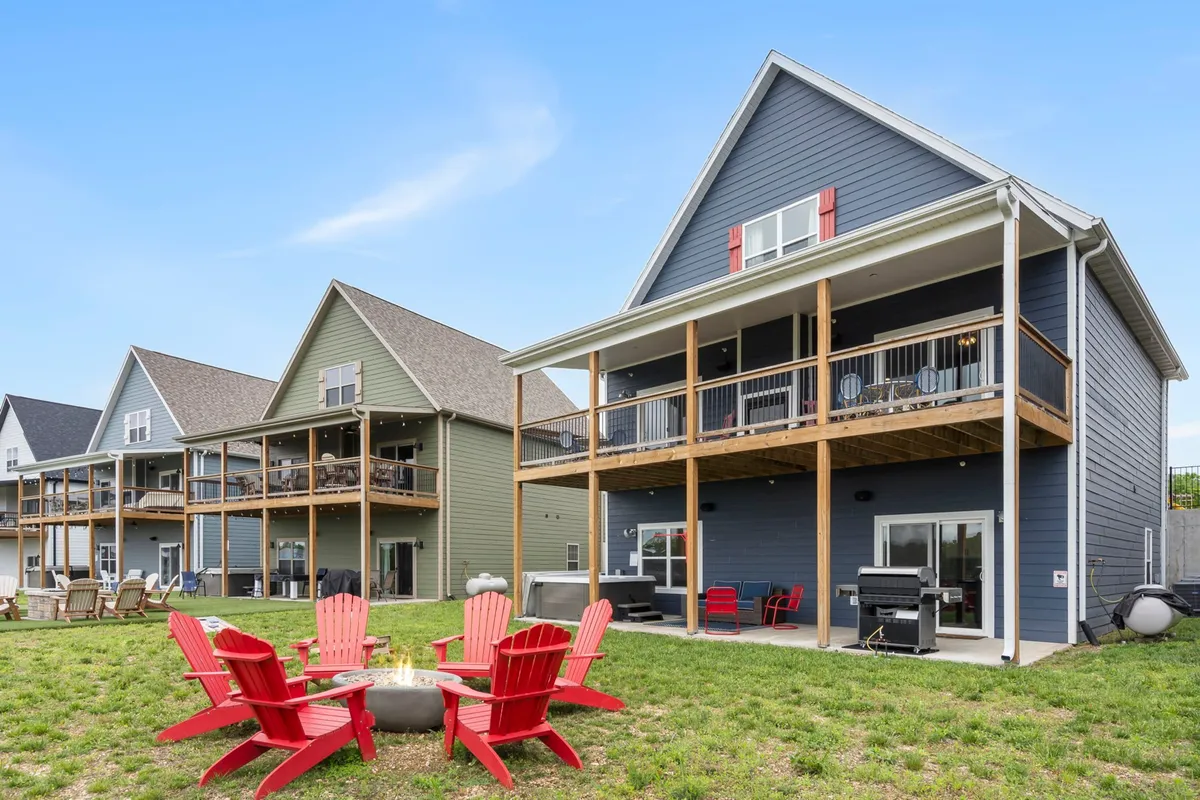 This image features a group of red Adirondack chairs gathered around a fire pit in front of Dogwood Place, with balconies visible on the homes. The setting is outdoors, capturing sunset hues, and evokes the atmosphere of relaxation and social gatherings after a day of exploration.
